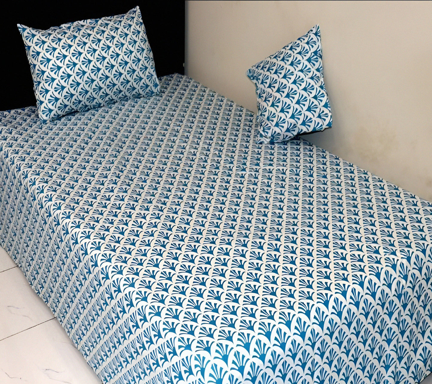 Bedspread with blue and white geometric pattern on a bed with matching pillows.