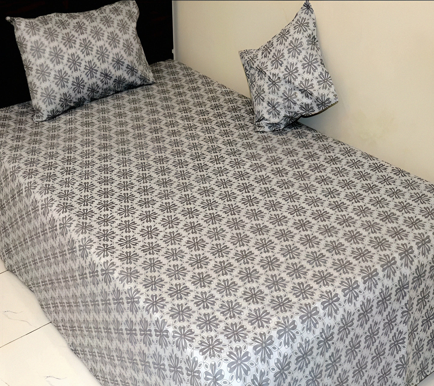 Floral patterned bedsheet with matching pillows on a bed.