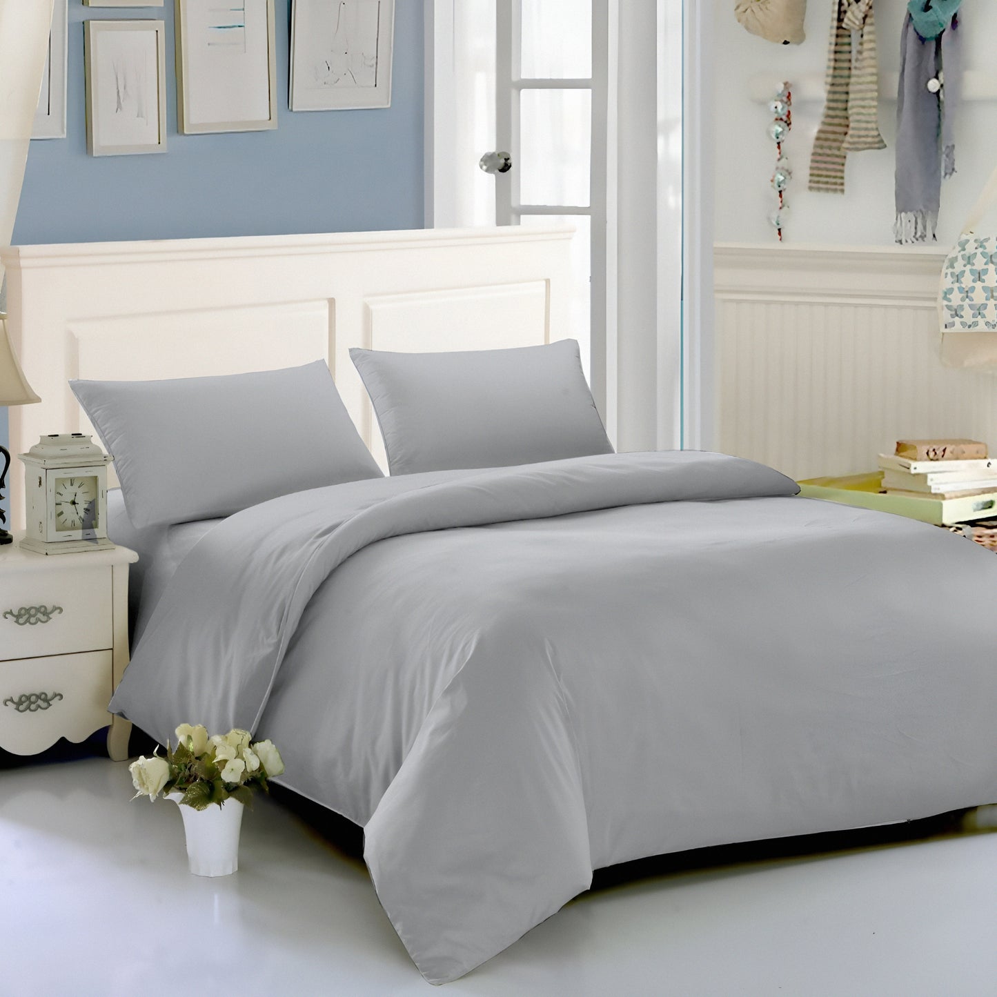 Gray bedding set on a bed in a bedroom with light blue walls and white furniture.