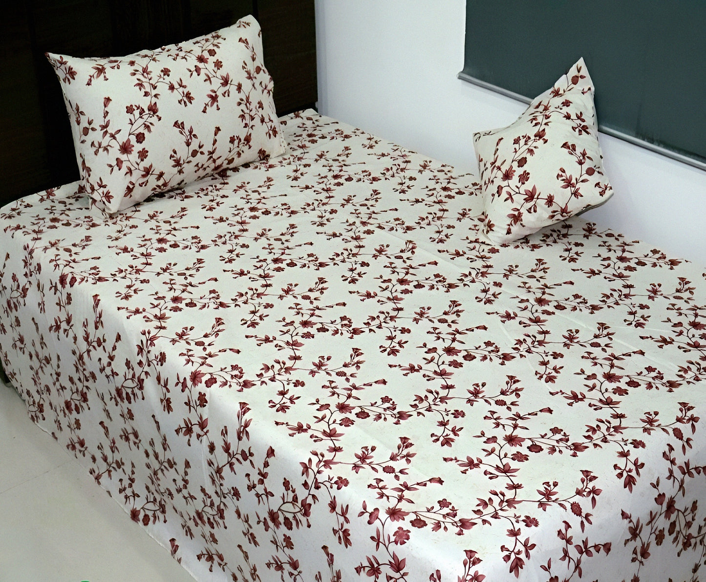 Floral patterned bedsheet with matching pillows on a bed.