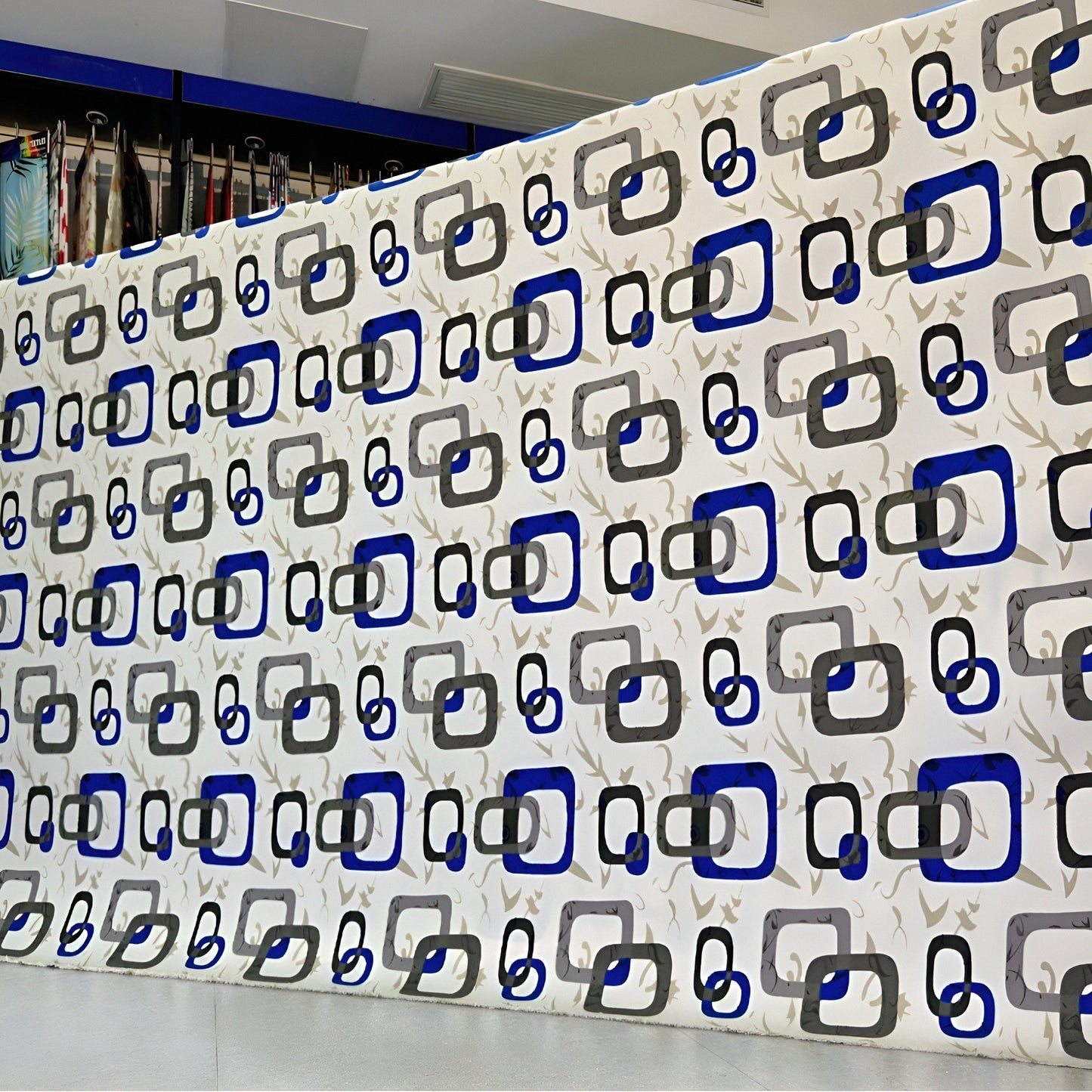 Wall with geometric pattern of blue, black, and gray squares in a store setting.