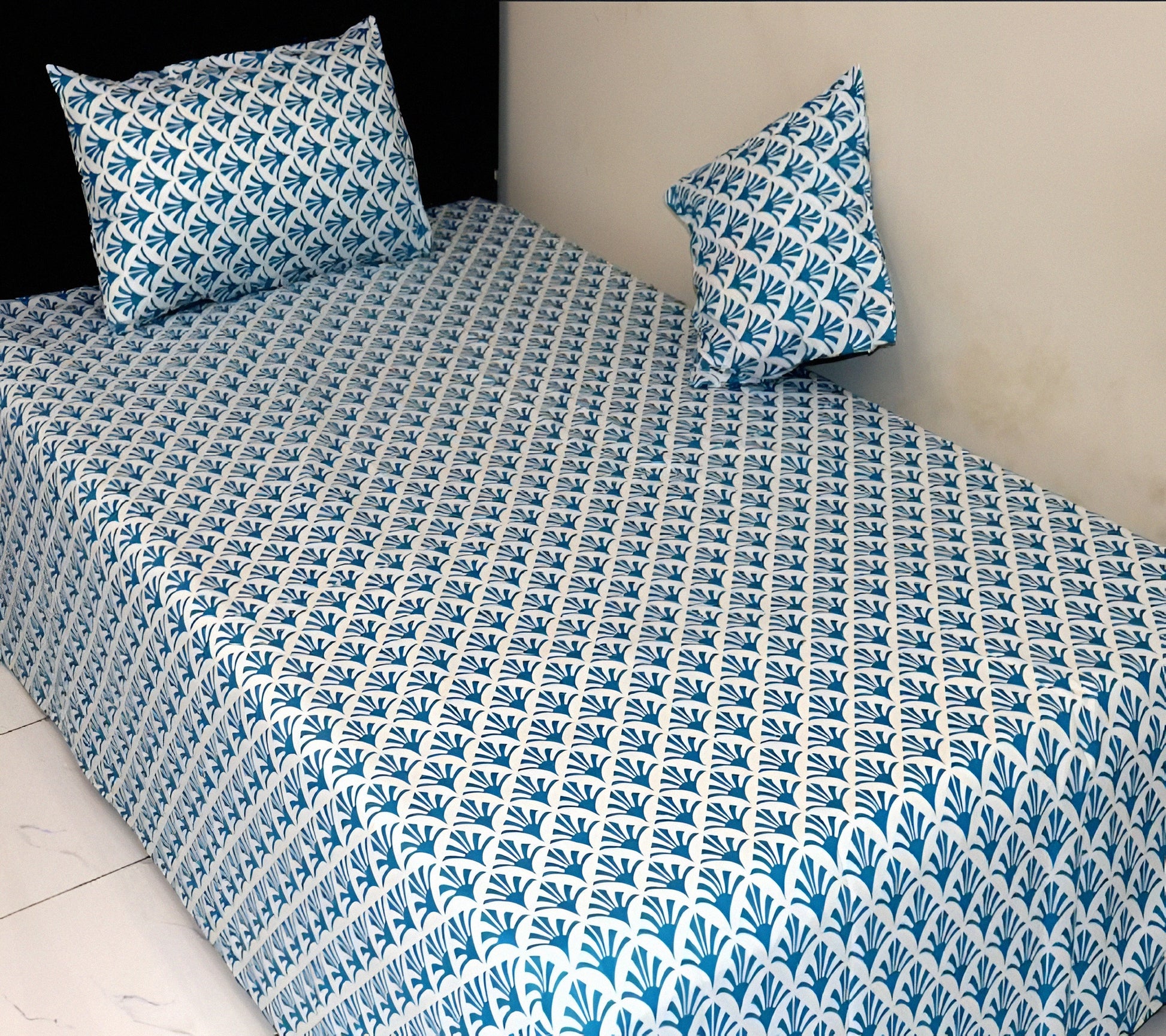 Bedspread with blue and white geometric pattern on a bed with matching pillows.