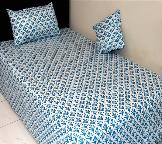 Bedspread with blue and white geometric pattern on a bed with matching pillows.