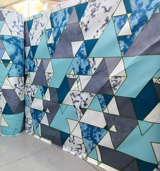 Geometric cyan, gray and white mixed-cotton bedsheet roll with triangle pattern, displayed for wholesale buyers.