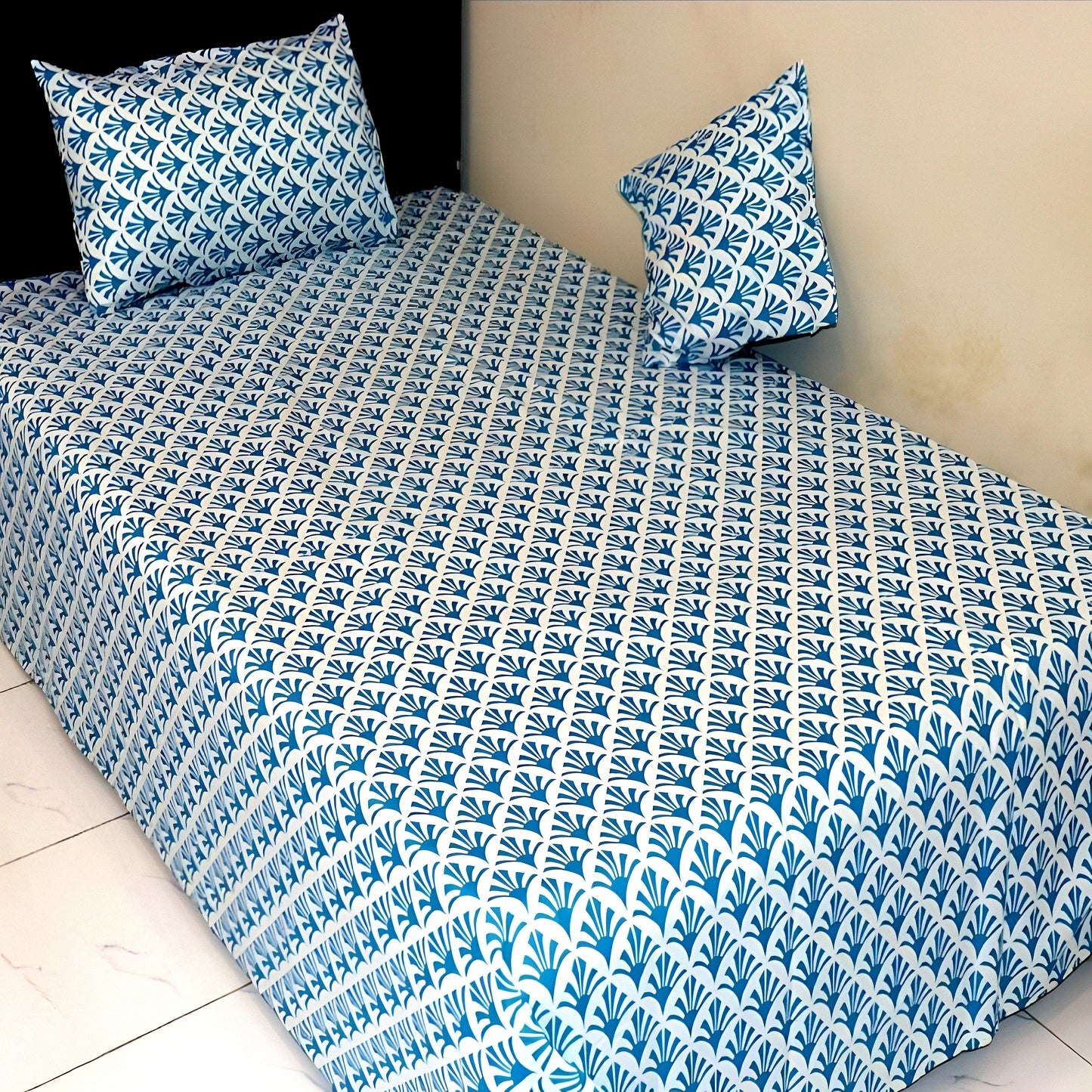 Blue and white patterned bedspread on a bed with matching pillows.