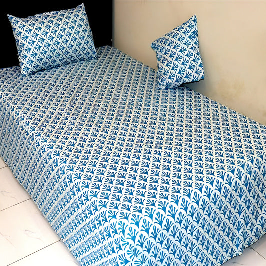 Blue and white patterned bedspread on a bed with matching pillows.