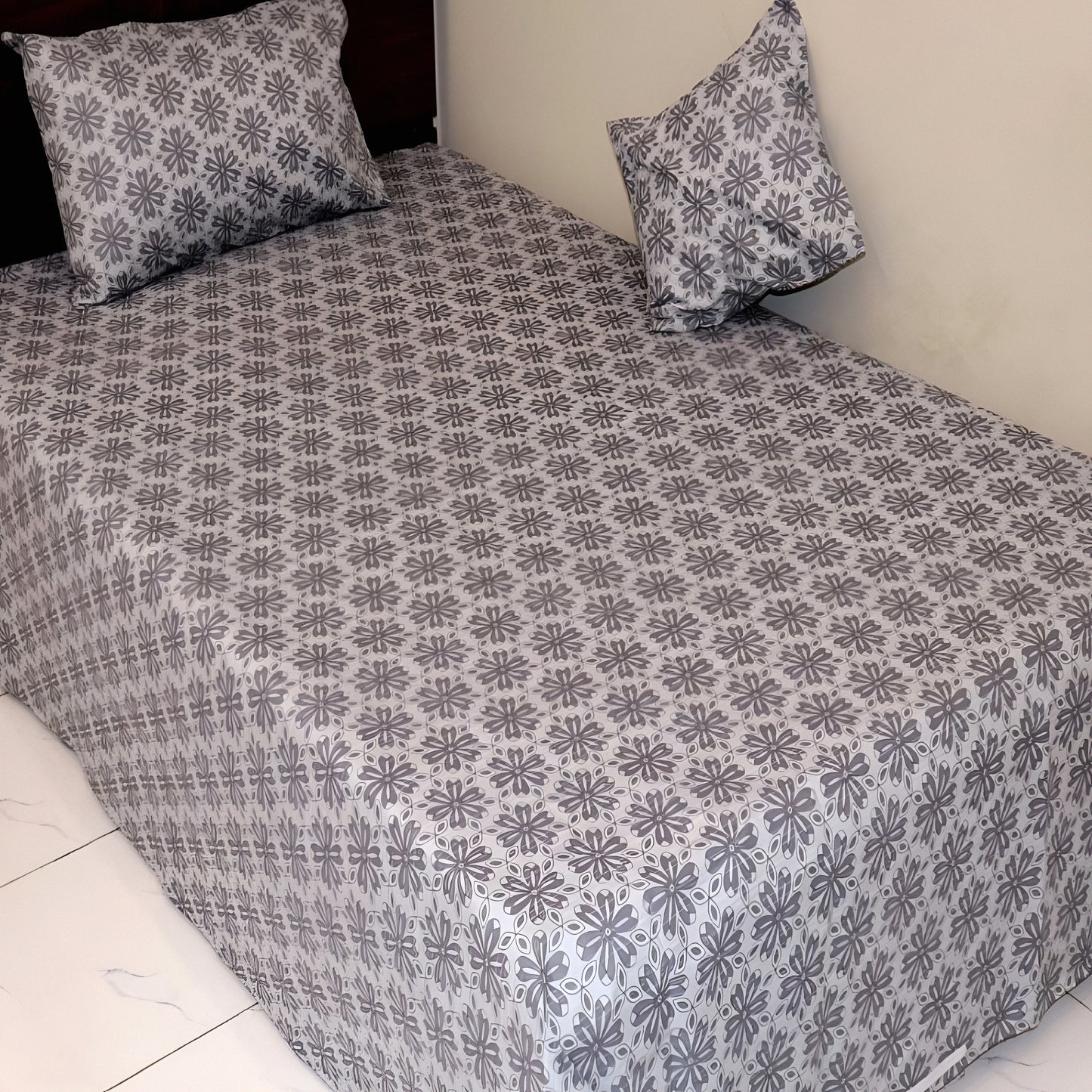 Floral patterned bedsheet with matching pillows on a bed.