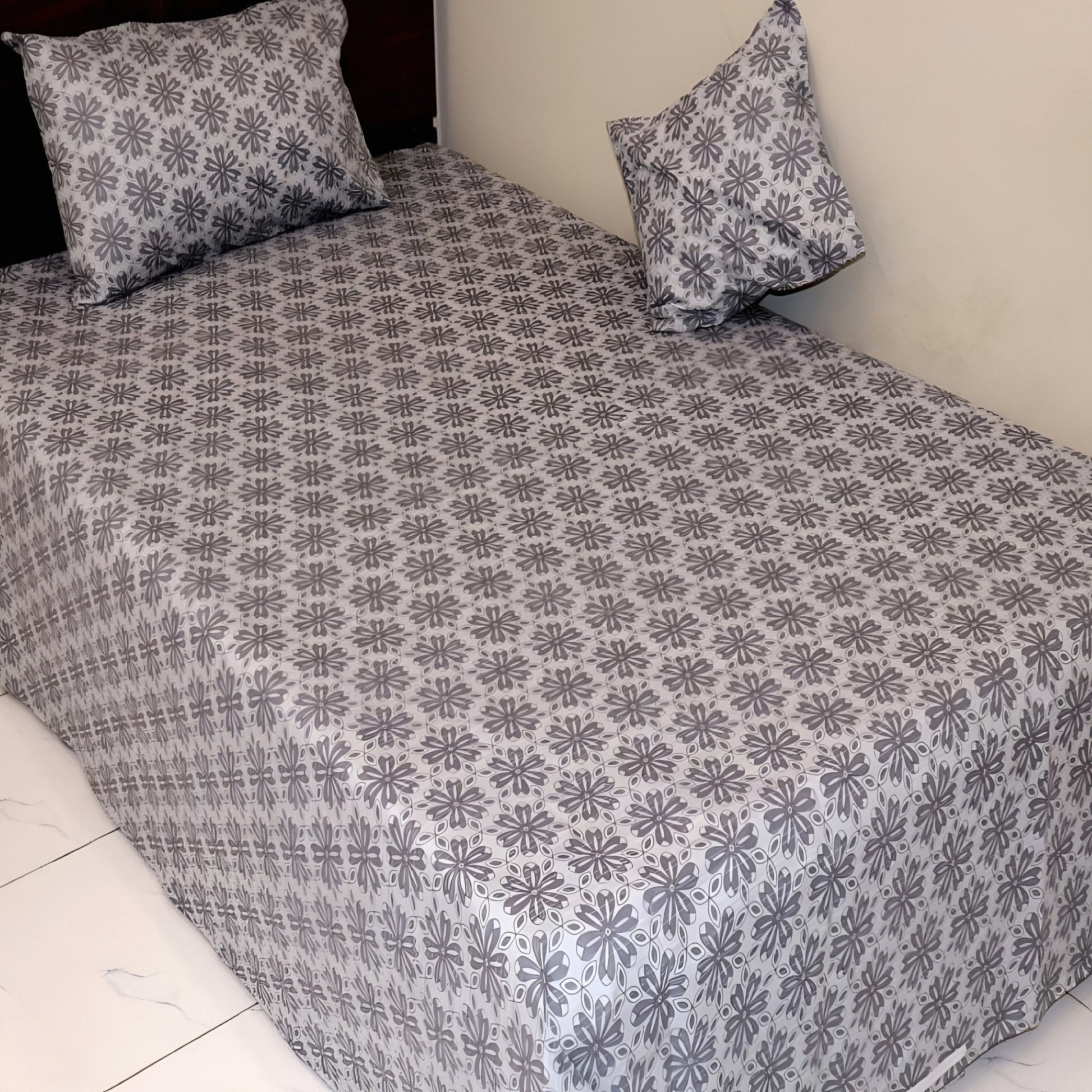 Floral patterned bedsheet with matching pillows on a bed.