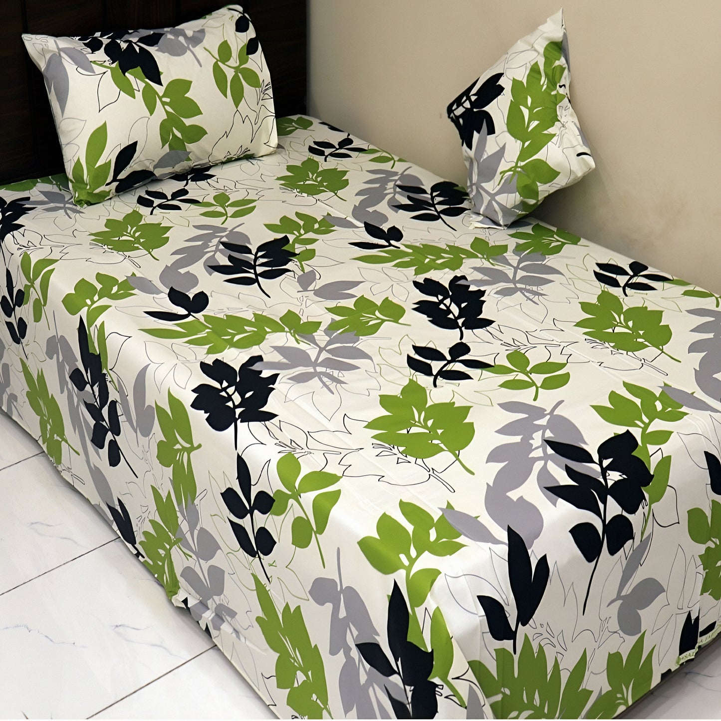 Single bed dressed with green leaf printed cotton bedsheet and matching pillow cover.