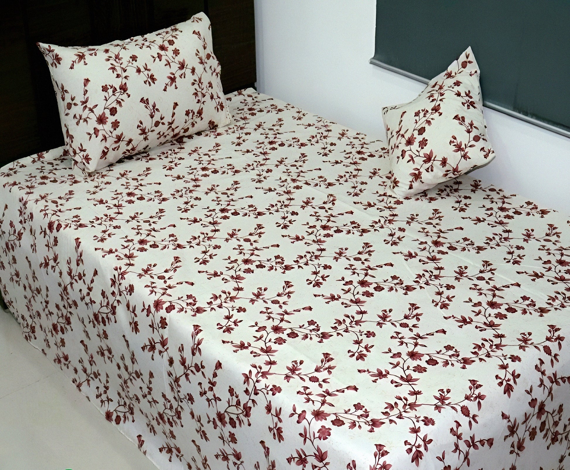 Floral patterned bedsheet with matching pillows on a bed.