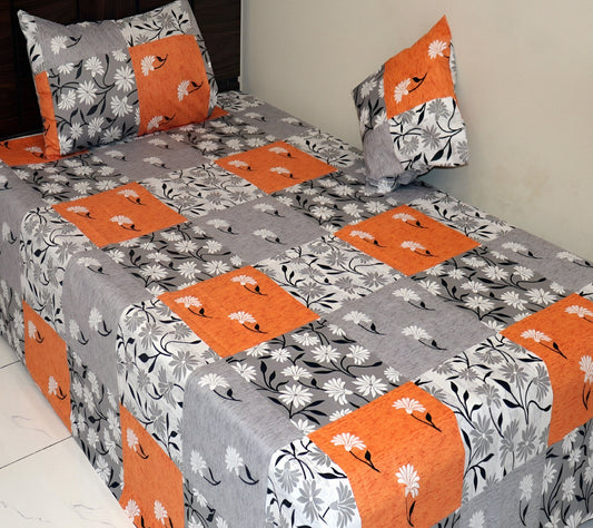 Off-white floral cotton bedsheet with grey and orange patchwork design on a made bed with matching pillowcases.