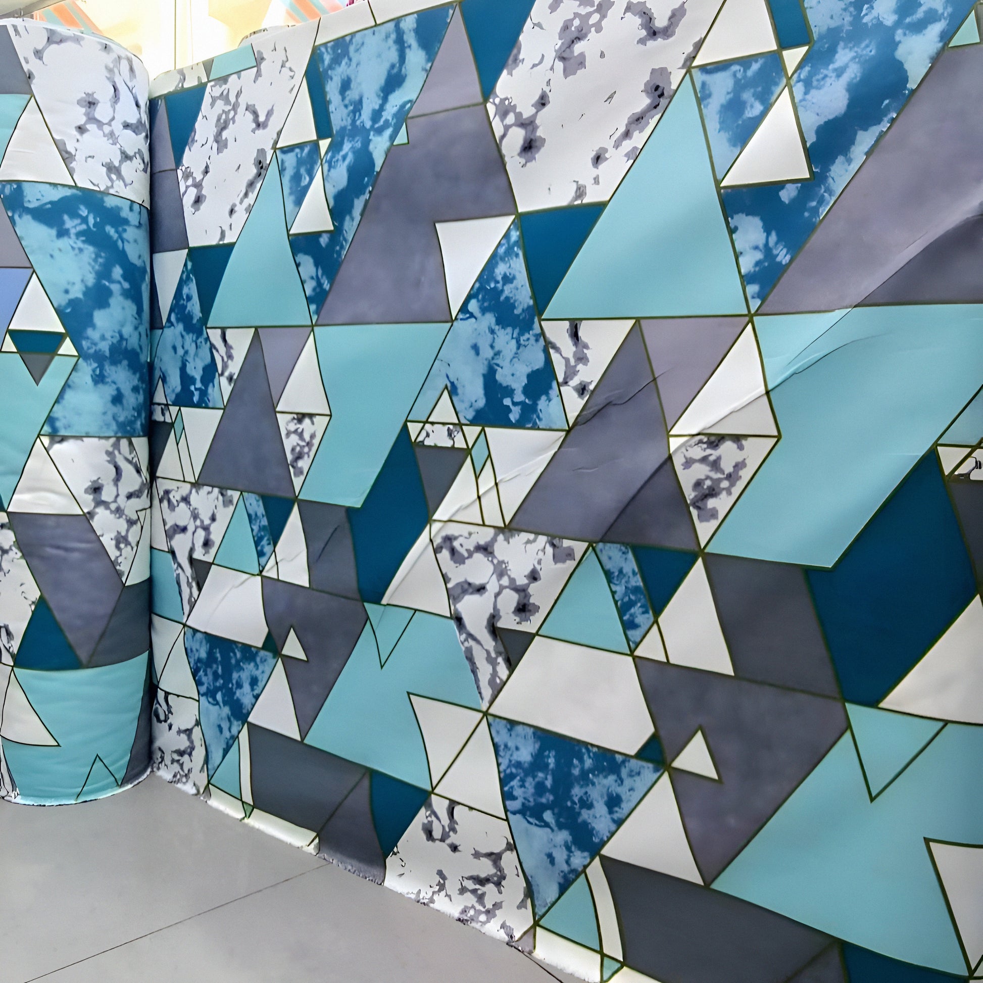 Geometric cyan, gray and white mixed-cotton bedsheet roll with triangle pattern, displayed for wholesale buyers.