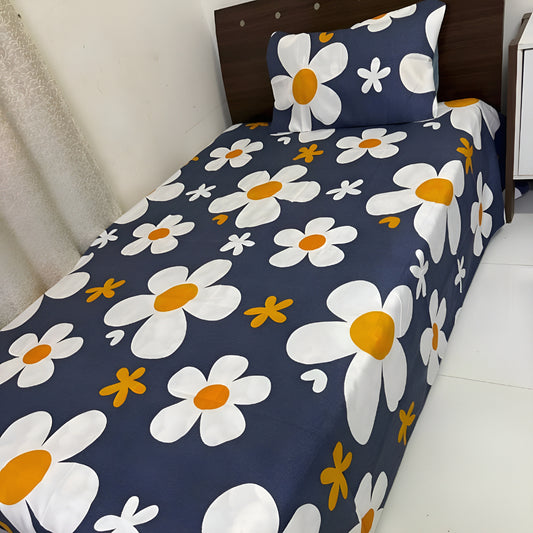 Floral bedspread with white flowers and orange centers on a blue background, placed on a bed.